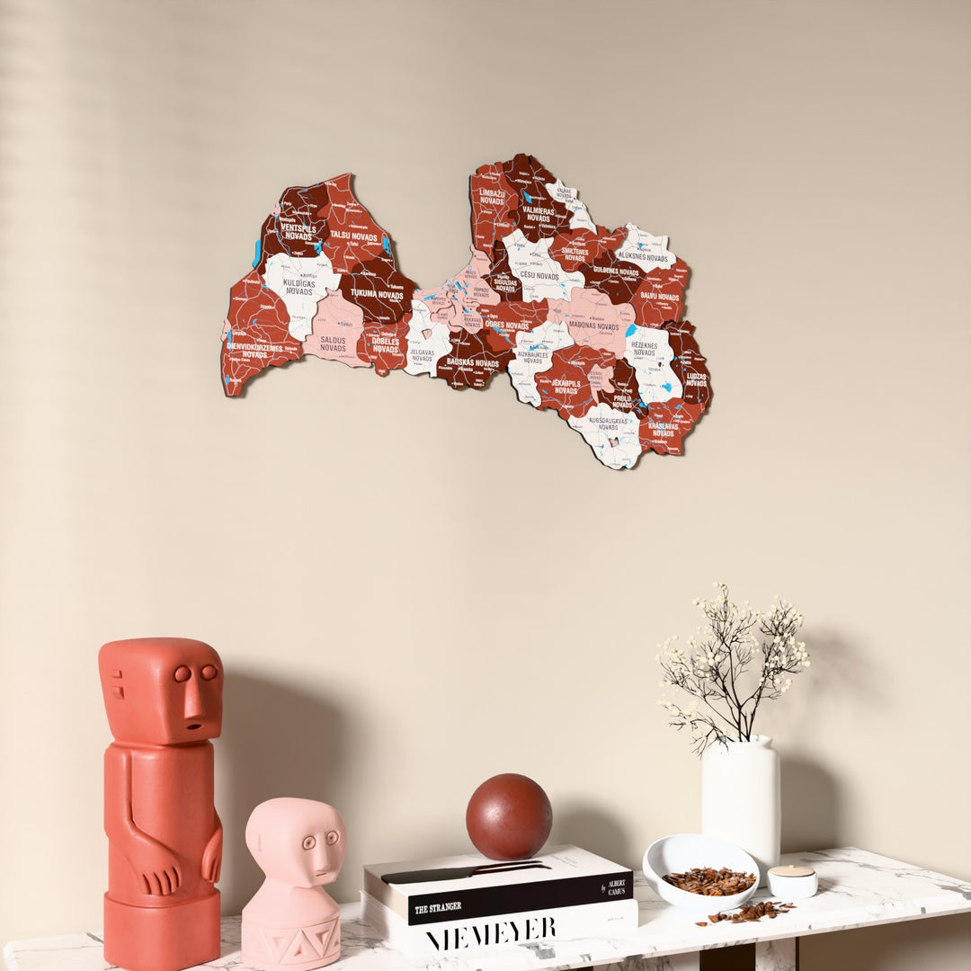 Flag colored Latvia wooden wall map on a beige wall above a console with figurines