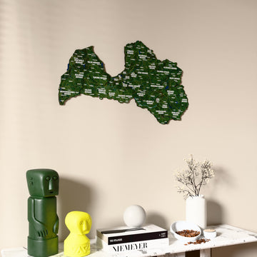 Satellite Latvia wooden wall map on a beige wall above a console with figurines