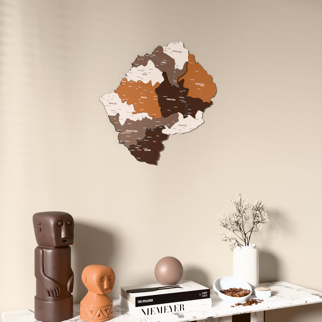 Soil Lesotho wooden wall map on a beige wall above a console with figurines