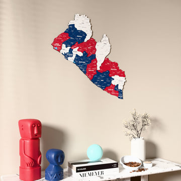 Flag colored Liberia wooden wall map on a beige wall above a console with figurines