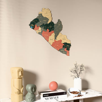 Sage Liberia wooden wall map on a beige wall above a console with figurines