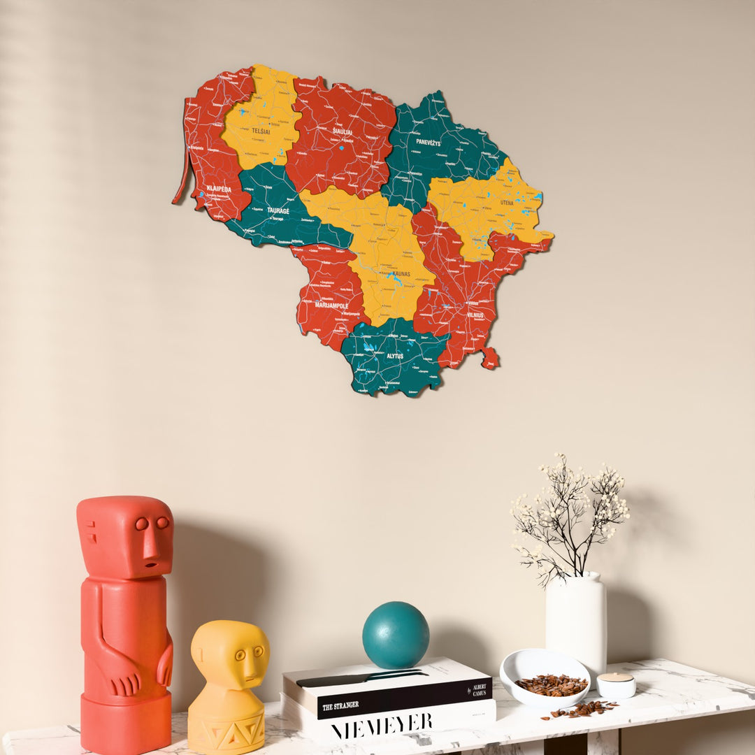 Flag colored Lithuania wooden wall map on a beige wall above a console with figurines