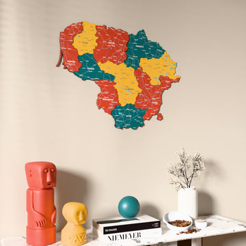 Flag colored Lithuania wooden wall map on a beige wall above a console with figurines