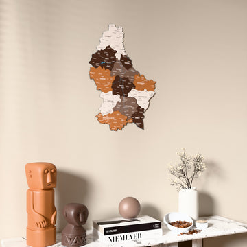 Soil Luxembourg wooden wall map on a beige wall above a console with figurines