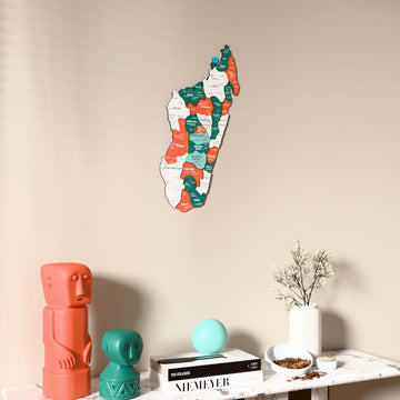 Flag colored Madagascar wooden wall map on a beige wall above a console with figurines