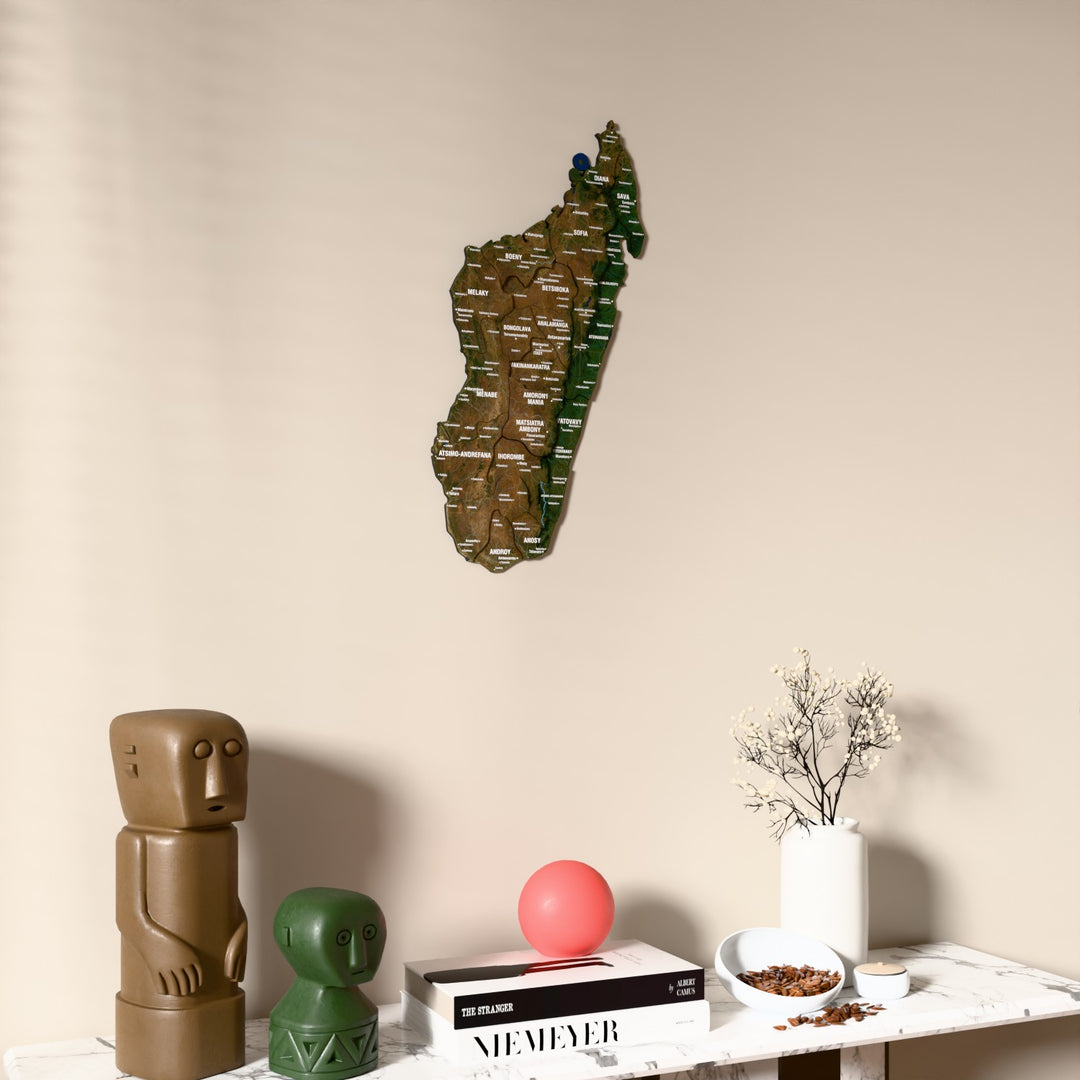 Satellite Madagascar wooden wall map on a beige wall above a console with figurines