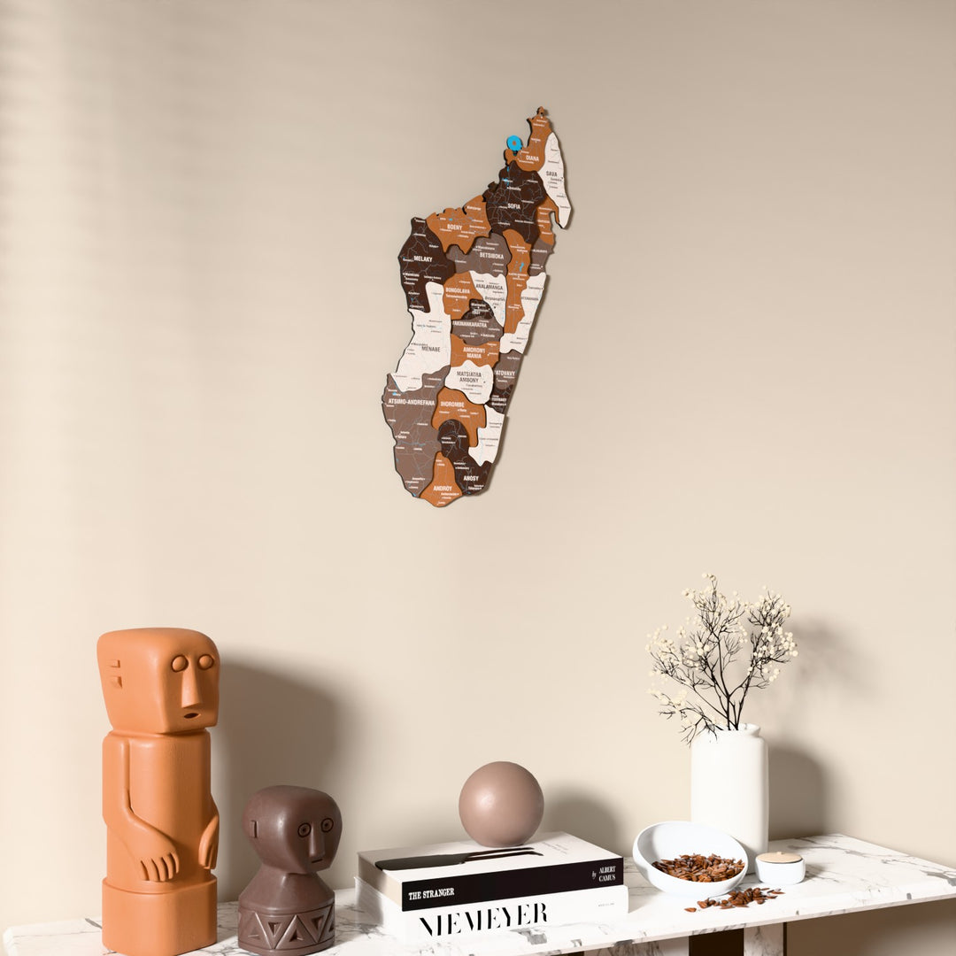 Soil Madagascar wooden wall map on a beige wall above a console with figurines