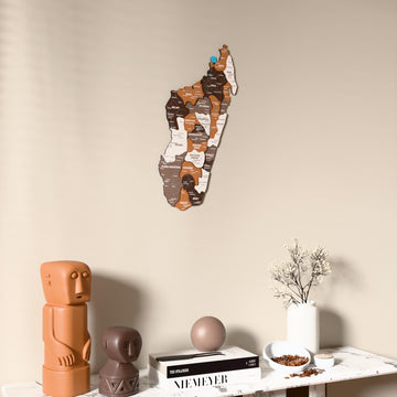 Soil Madagascar wooden wall map on a beige wall above a console with figurines