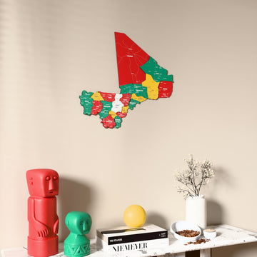 Flag colored Mali wooden wall map on a beige wall above a console with figurines