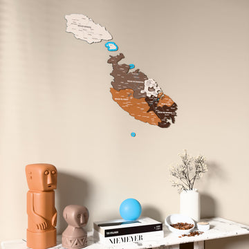 Soil Malta wooden wall map on a beige wall above a console with figurines