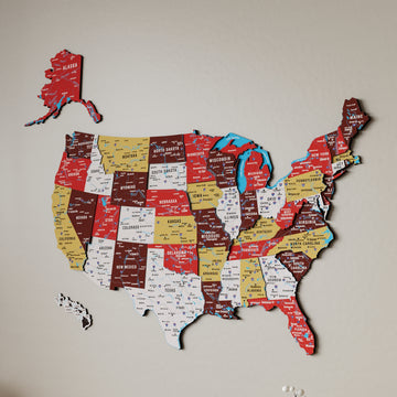 Large terracotta United States wooden wall map on a beige wall, showing Alaska, Hawaii and layered state panels
