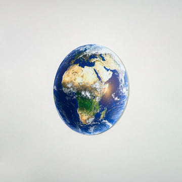 Small metal Earth wall art showing Africa on a light gray wall, angled view