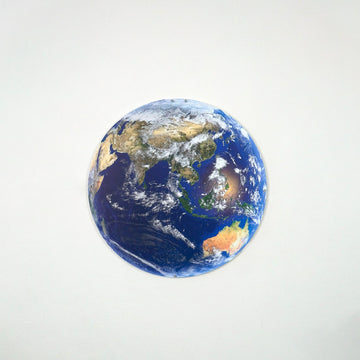 Round metal Earth wall art showing Asia and Australia on a light wall, straight-on view
