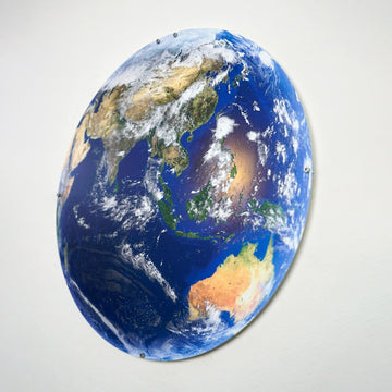 UV-printed metal wall art of Earth showing Asia and Australia from space, tilted oval view