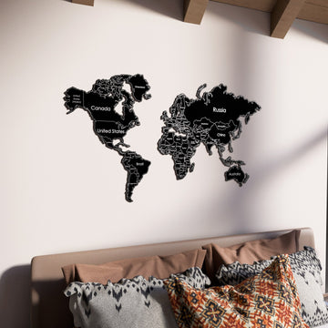 Black metal world map above a bed with patterned pillows