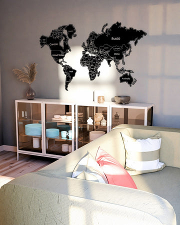 Black metal world map above a glass-door cabinet and sofa, tall crop
