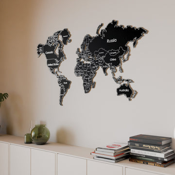Black metal world map above a white sideboard with a green vase