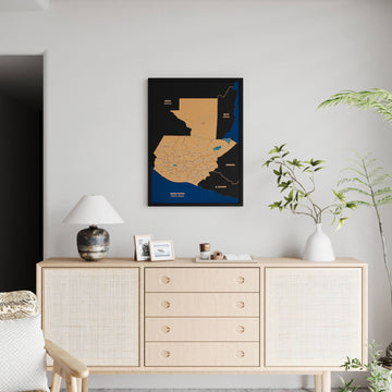 Small black-framed Guatemala cork map on a light wall, far view with a full rattan sideboard below