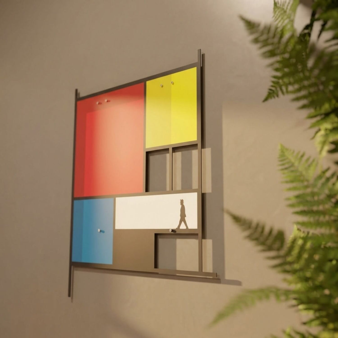 Mondrian-style metal wall art among fern leaves, side angle