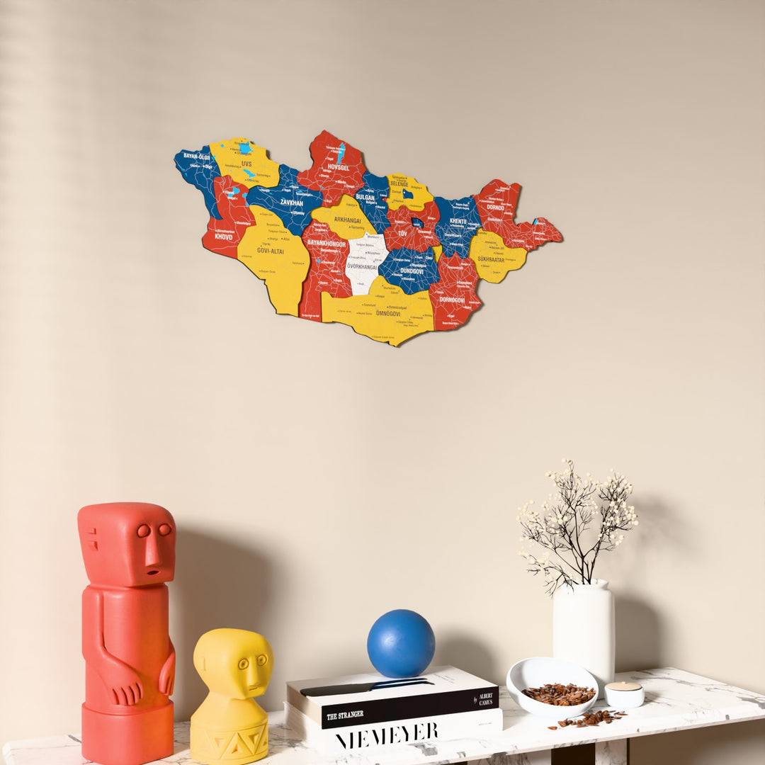Flag colored Mongolia wooden wall map on a beige wall above a console with figurines