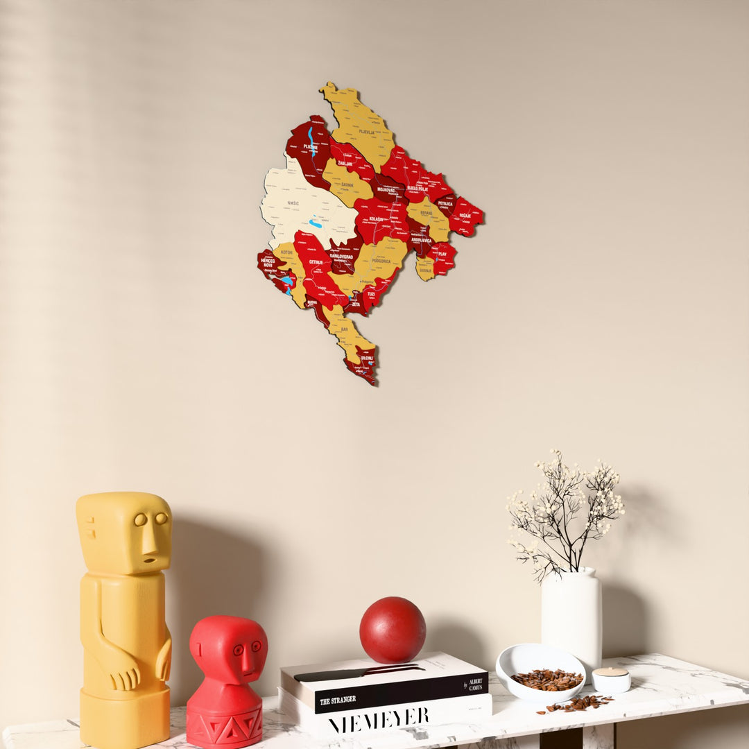 Flag colored Montenegro wooden wall map on a beige wall above a console with figurines