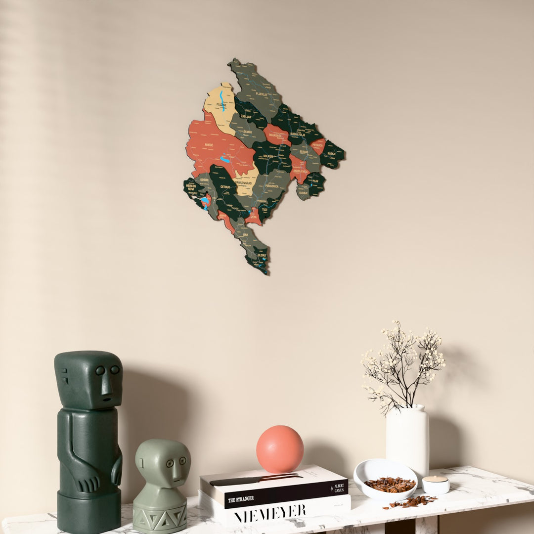 Sage Montenegro wooden wall map on a beige wall above a console with figurines