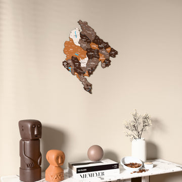 Soil Montenegro wooden wall map on a beige wall above a console with figurines