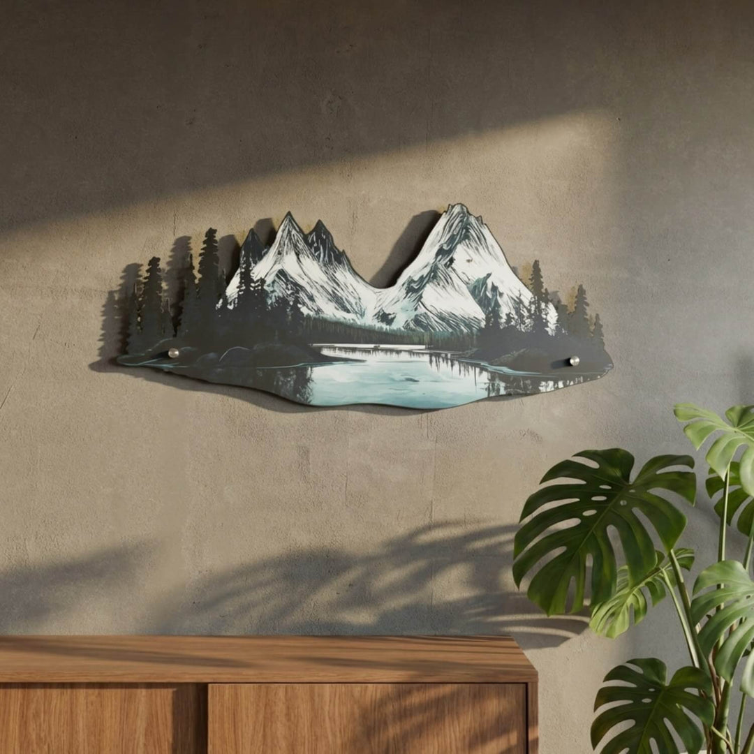 Mountain and river metal wall art next to a monstera and wooden sideboard
