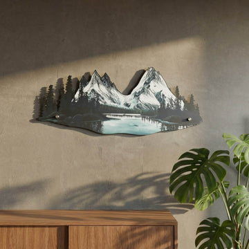 Mountain and river metal wall art next to a monstera and wooden sideboard