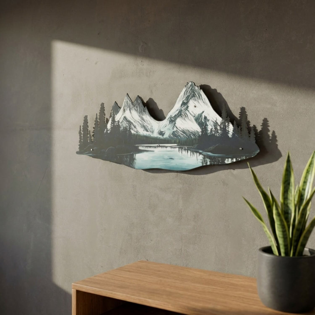 Mountain and river metal wall art on a wall, side view next to a plant