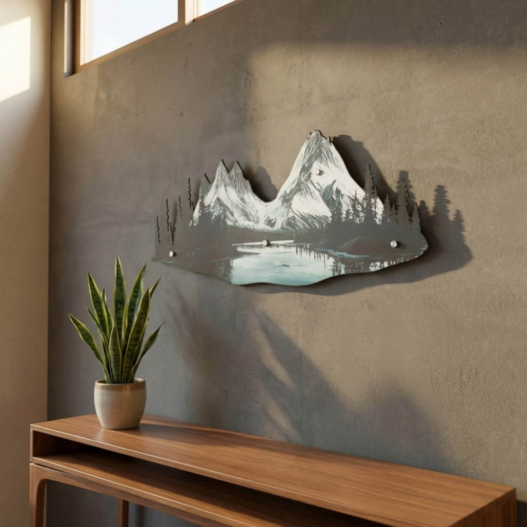 Mountain and river metal wall art in window light above a snake plant