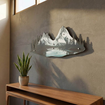 Mountain and river metal wall art in window light above a snake plant