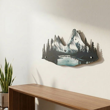 Mountain and river metal wall decor on a light wall with a wooden table