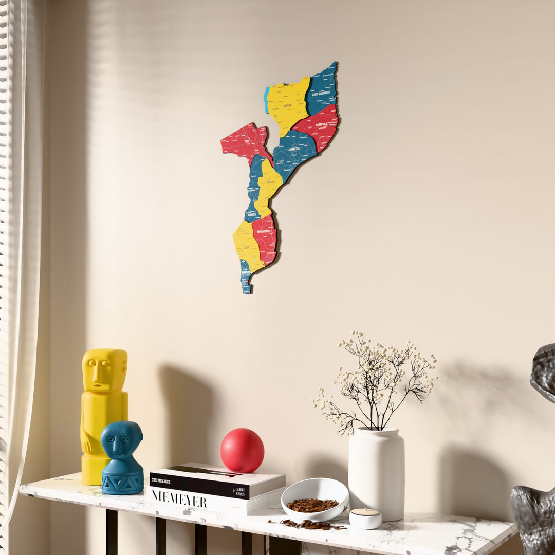 Flag colored Mozambique wooden wall map beside a sheer curtain, angled view