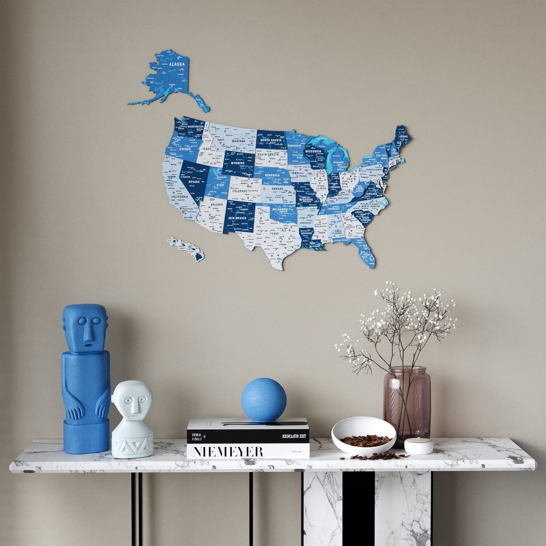 A blue and white USA state map wall decor piece mounted on a beige wall above a marble console table with decorative objects.