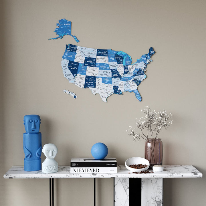 A blue and white USA state map wall decor piece mounted on a beige wall above a marble console table with decorative objects.
