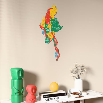 Flag colored Myanmar wooden wall map on a beige wall above a console with figurines