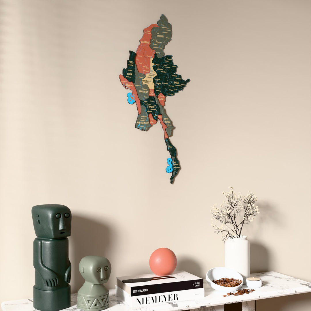 Sage Myanmar wooden wall map on a beige wall above a console with figurines