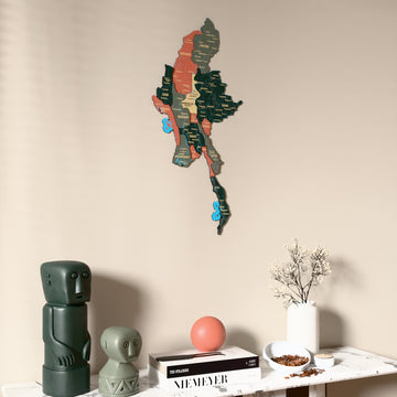 Sage Myanmar wooden wall map on a beige wall above a console with figurines