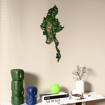 Satellite Myanmar wooden wall map on a beige wall above a console with figurines