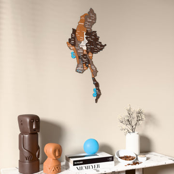 Soil Myanmar wooden wall map on a beige wall above a console with figurines