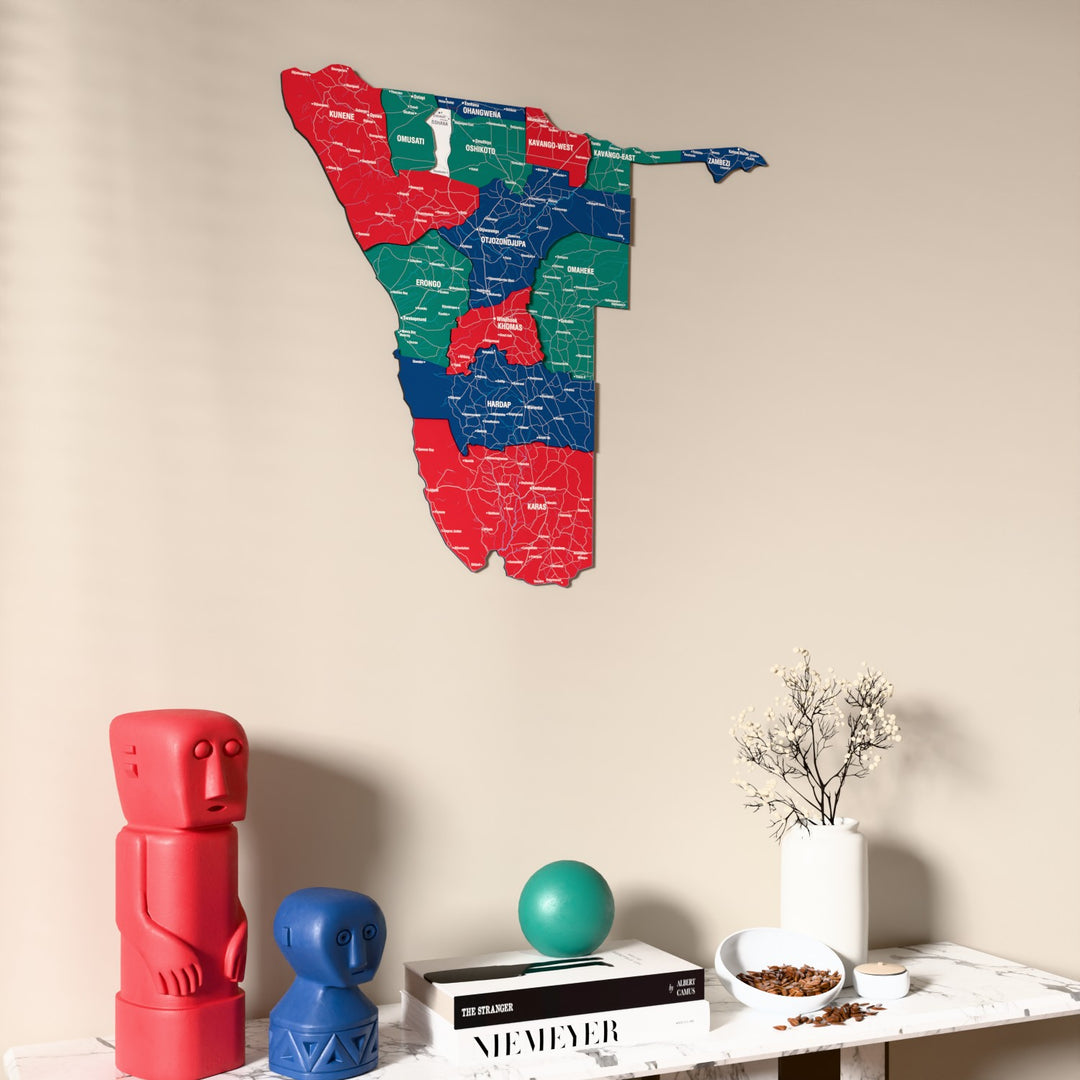 Flag colored Namibia wooden wall map on a beige wall above a console with figurines