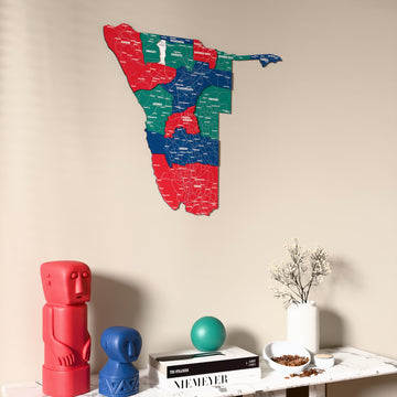 Flag colored Namibia wooden wall map on a beige wall above a console with figurines