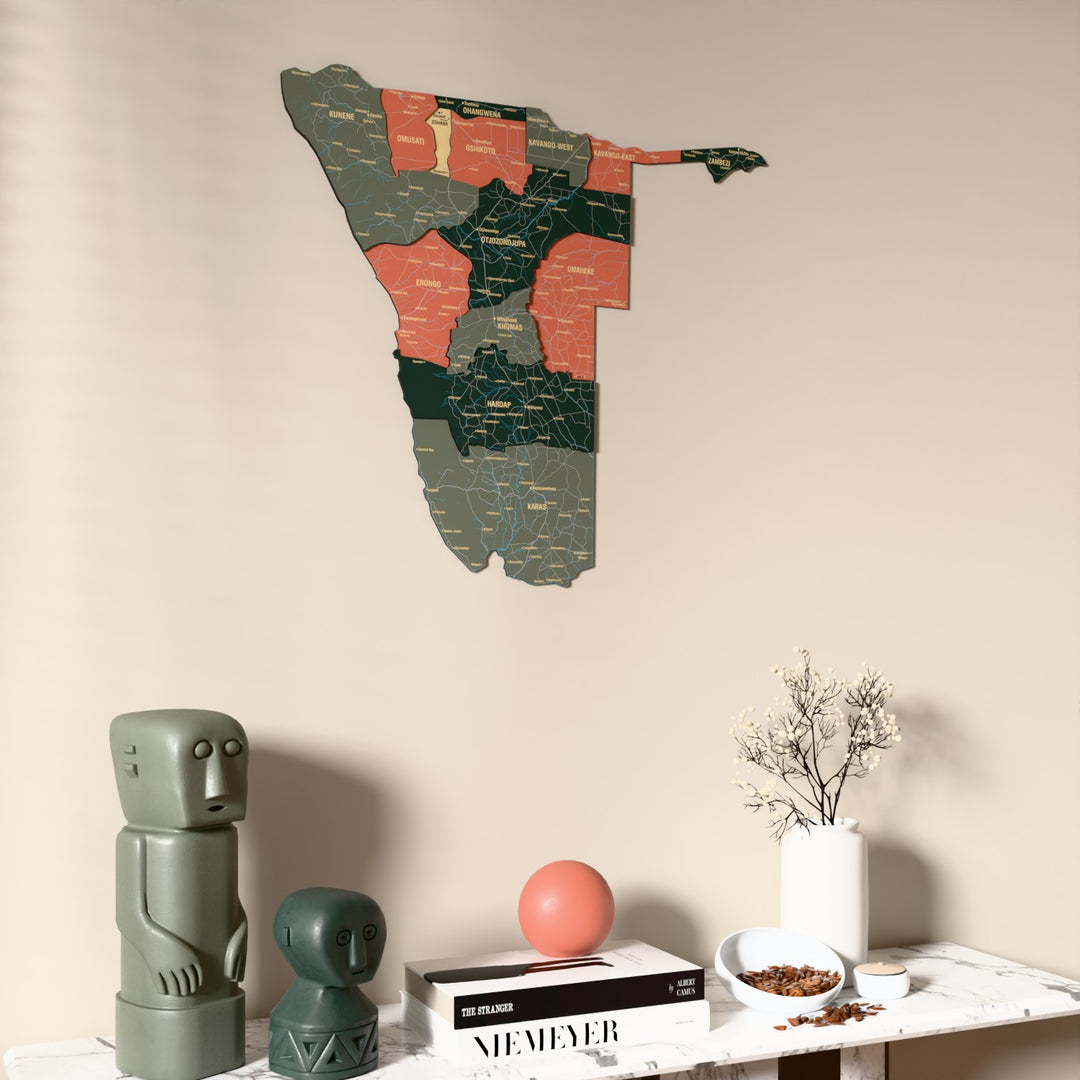 Sage Namibia wooden wall map on a beige wall above a console with figurines