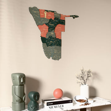 Sage Namibia wooden wall map on a beige wall above a console with figurines