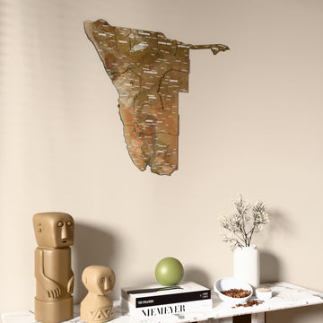 Satellite Namibia wooden wall map on a beige wall above a console with figurines