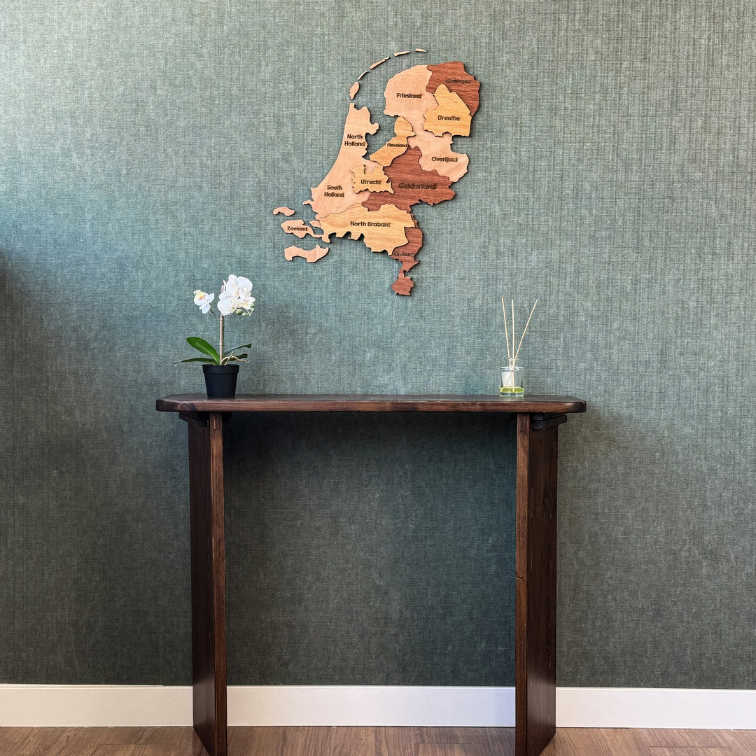 Wooden Netherlands map centered above a tall console table with white baseboard