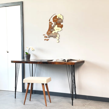 Netherlands wooden wall map on a white wall above a hairpin-leg desk, door frame at left