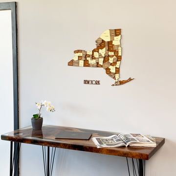 New York wooden wall map on a gray wall above a dark desk