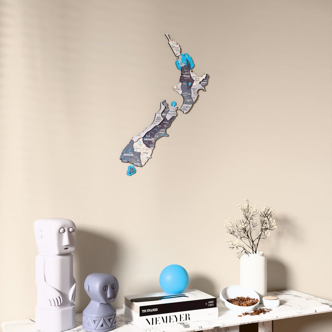 Nimbus New Zealand wooden wall map on a beige wall above a console with figurines